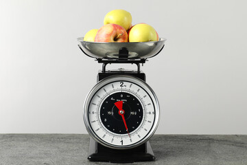 Retro mechanical kitchen scale with apples on grey table