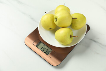 Modern electronic kitchen scale with apples on white marble table, closeup