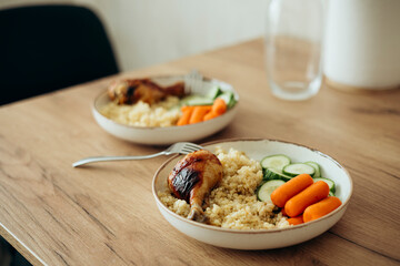 Bulgur, fresh vegetables and chicken drumstick on a plate for lunch at home.
