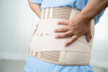 Asian senior pain back wearing elastic support belt with walker.