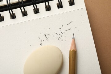 Eraser, pencil, scraps and notebook on brown background, top view