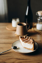 Piece of cheesecake with caramel topping on ceramic plate on wooden table.