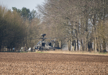 British army AH-64E Boeing Apache Attack helicopter gunship (ZM735 ArmyAirCorp) taking off from inside a woodland copse