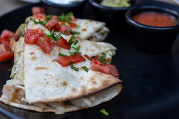 Delicious Chicken Quesadilla with Toppings on a Black Plate