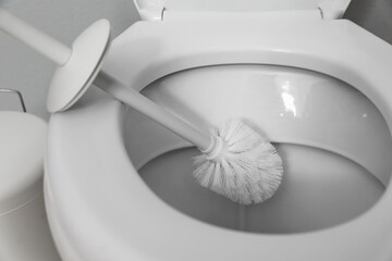 Cleaning toilet bowl with brush indoors, closeup