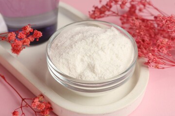 Collagen powder in bowl and gypsophila branches on pink background, closeup