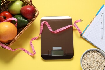 Electronic kitchen scale, measuring tape, notebook and products on yellow background, flat lay....