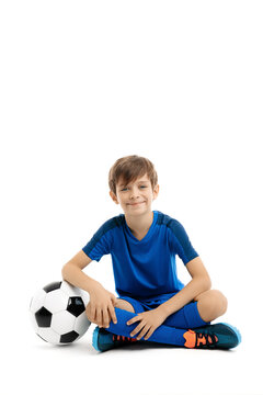 Smiling young boy posing with classic soccer ball on the floor over white background