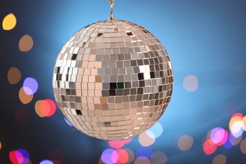 Shiny disco ball on blue gradient background with blurred lights