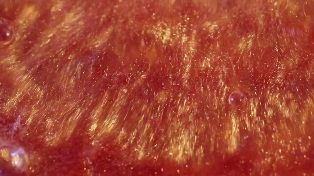 liquid with dissolved particles of orange candurin is bubbling and mixing vigorously. abstract bright background