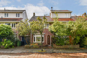 A picturesque view of a residential area featuring cozy homes surrounded by vibrant green trees and shrubs, creating a serene atmosphere.