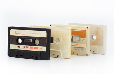 Obraz premium A row of vintage cassette tapes with faded labels on a white background, evoking retro audio nostalgia.