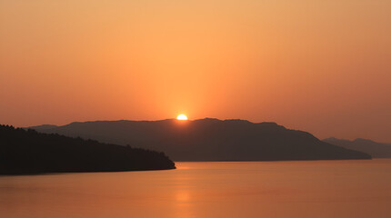 Naklejka premium A peaceful sunrise over a tranquil lake with mountains in the background, soft pastel colors in the sky