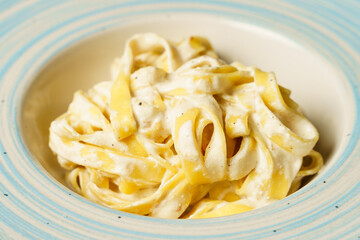 Classic spaghetti cacio e pepe with grated cheese on a blue-striped plate