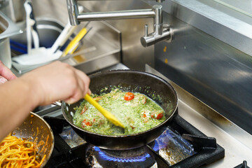 Chef preparing creamy pesto sauce with cherry tomatoes