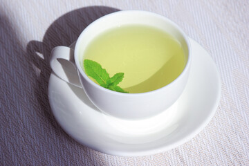 White cup and saucer with mint tea