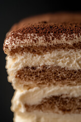 Close-up of a layered tiramisu dessert with coffee-soaked ladyfingers, creamy mascarpone, and a dusting of cocoa powder.