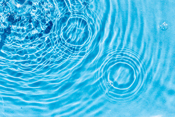 turquoise water surface with ripples and to circles in diagonal direction, wave clean transparent water in blue, abstract background