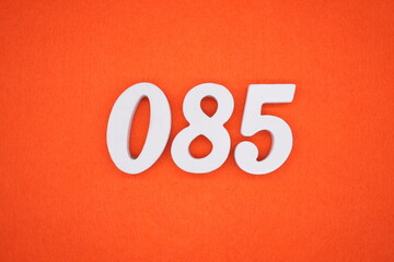 The numbers are made of white painted wood placed on an orange paper background.