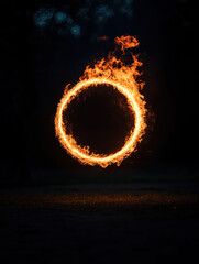 A vibrant ring of fire burns against a dark, almost black background with a hint of ground below.