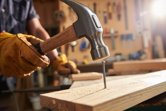 Craftsman hammering a nail into wood in a workshop  