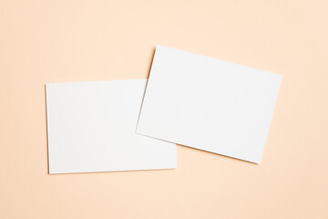 Two blank white horizontal cards placed on a beige surface with a slight overlap, ideal for wedding...