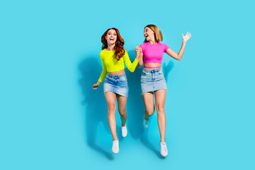 Obraz premium Vibrant and joyful image of fashionable young women on a teal background, embracing summer style and friendship