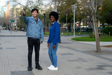 Two friends standing in a city street, smiling and gesturing, enjoying a casual moment outdoors