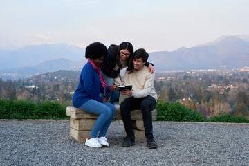 Three diverse friends enjoying a relaxing day outdoors, bonding over a book while surrounded by nature and mountains