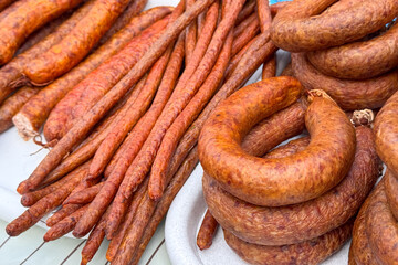 A colorful display of cured sausages, including long thin varieties and coiled rings