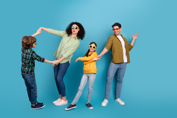 Fototapeta premium Cheerful family posing playfully against a vibrant blue background, showcasing their stylish outfits and expressing joy