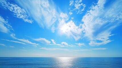 Obraz premium Bright blue sky featuring clouds over a calm ocean scene