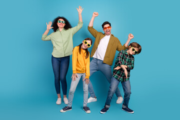 Cheerful family group wearing casual outfits, expressing joy and fun together against a bright blue...