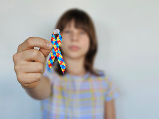 Child holds colorful awareness ribbon for autism