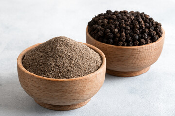 Ground black pepper with grains of black pepper on light background