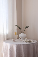 A stylish and aesthetically pleasing arrangement of twigs in ceramic vase, ceramic rabbit, easter decor displayed on a minimalist surface.