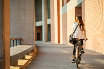 Young Asian business woman riding bicycle in urban city. Sustainable save energy lifestyle. Commute...