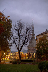 A park at dusk in Giardini Reali di Torino with bare trees and illuminated pathways, featuring the...