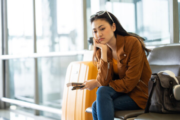 Unhappy young woman traveler disappointed with flight delay or cancelation while waiting at airport...