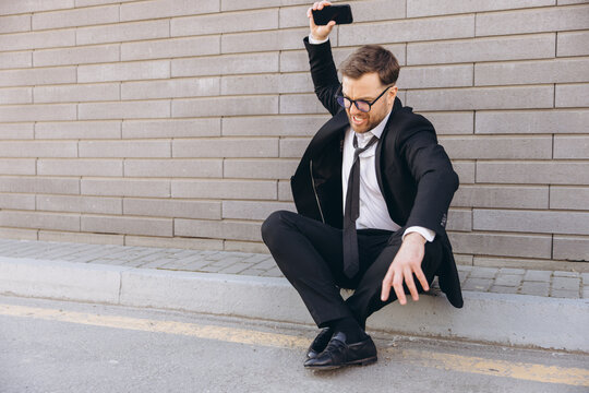 Frustrated businessman throwing smartphone on the street sidewalk