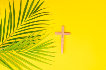 A wooden cross with bread on a palm leaves pattern, a Palm Sunday theme.
