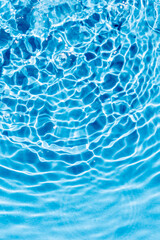 turquoise water surface with ripples and to circles in diagonal direction, wave clean transparent water in blue, abstract background, vertical shot