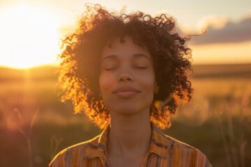 Backlit Portrait of calm happy smiling free woman with closed eyes enjoys a beautiful moment life on the fields at sunset