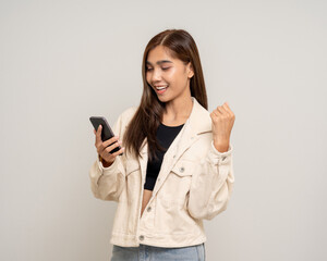 Fototapeta premium Pretty young asian woman using cellphone standing on isolated white background. Happy Excited Beautiful young asian shopping online payment with mobile phone. Playing game on smartphone
