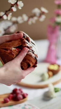A woman breaks cruffin, showing a fluffy, tender dough with a berry filling. cruffin with cherry jam. Easter bread. Easter eggs and spring flowers