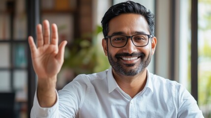 Fototapeta premium Smiling Man in Glasses Waving Hand in Office Setting, Positive Body Language, Professional Portrait