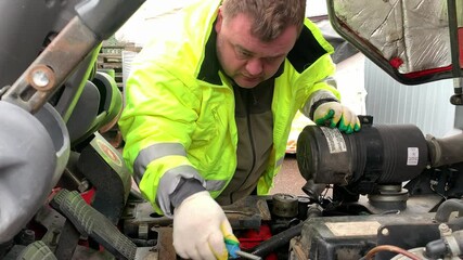 Car mechanic repairs a forklift. Mechanic services a car engine.
