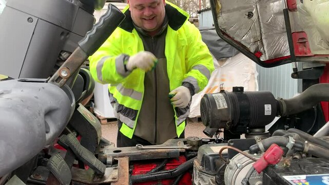 Car mechanic repairs a forklift. Mechanic services a car engine.
