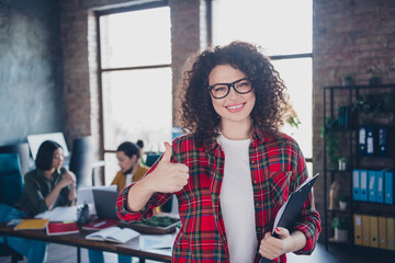 Smiling professional in a casual office environment giving a thumbs-up sign, symbolizing positivity