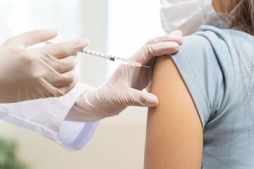 People getting a vaccination to prevent pandemic concept. Woman in medical face mask  receiving a dose of immunization coronavirus vaccine from a nurse at the medical center hospital